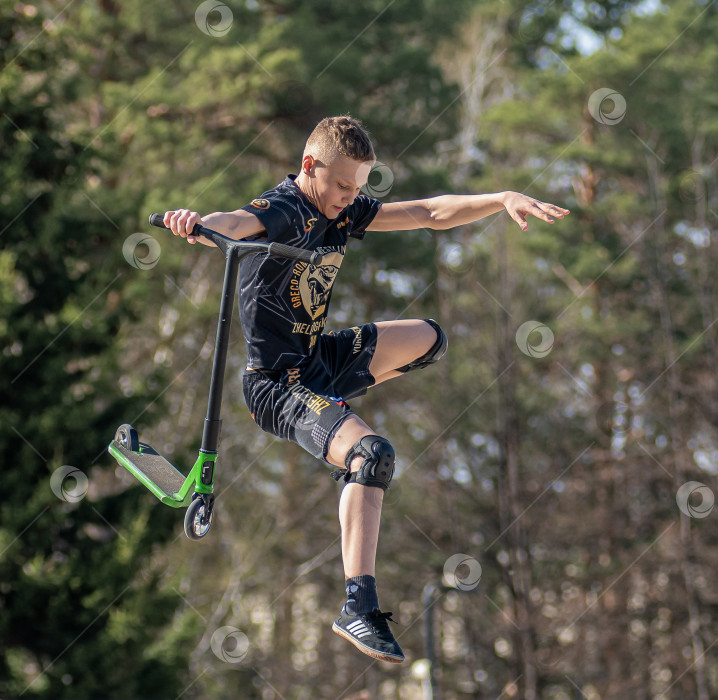 Скачать Россия, Красноярск 02 мая 2025г. Подросток на трюковом самокате в скейт-парке выполняет трюк во время прыжка. фотосток Ozero