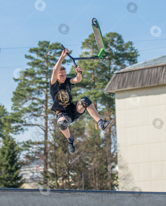 Скачать Россия, Красноярск 02 мая 2025г. Подросток на трюковом самокате в скейт-парке выполняет трюк во время прыжка. фотосток Ozero