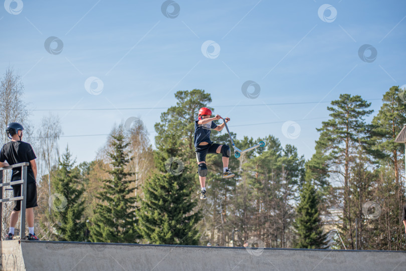 Скачать Россия, Красноярск 02 мая 2025г. Подросток на трюковом самокате в скейт-парке выполняет трюк во время прыжка. фотосток Ozero