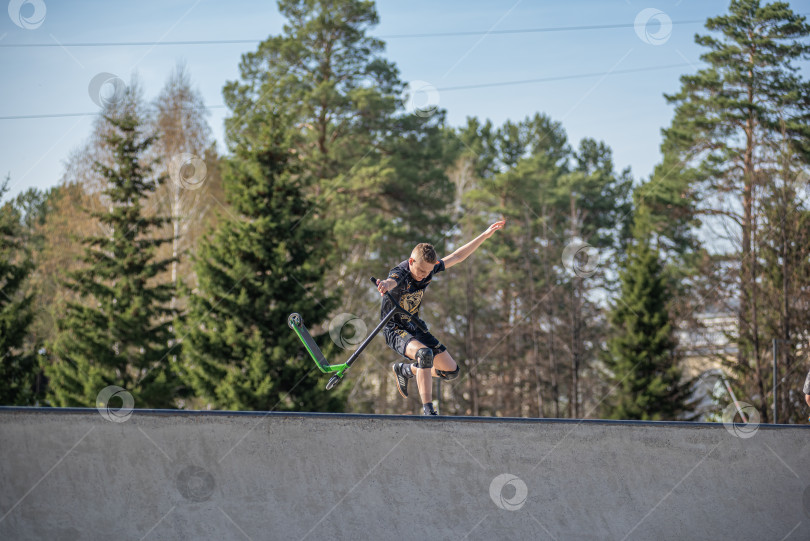 Скачать Россия, Красноярск 02 мая 2025г. Подросток на трюковом самокате в скейт-парке выполняет трюк во время прыжка. фотосток Ozero