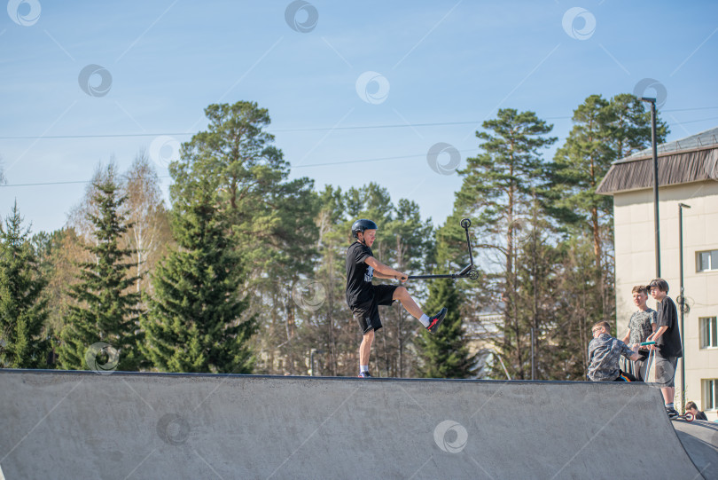 Скачать Россия, Красноярск 02 мая 2025г. Подросток на трюковом самокате в скейт-парке выполняет трюк во время прыжка. фотосток Ozero