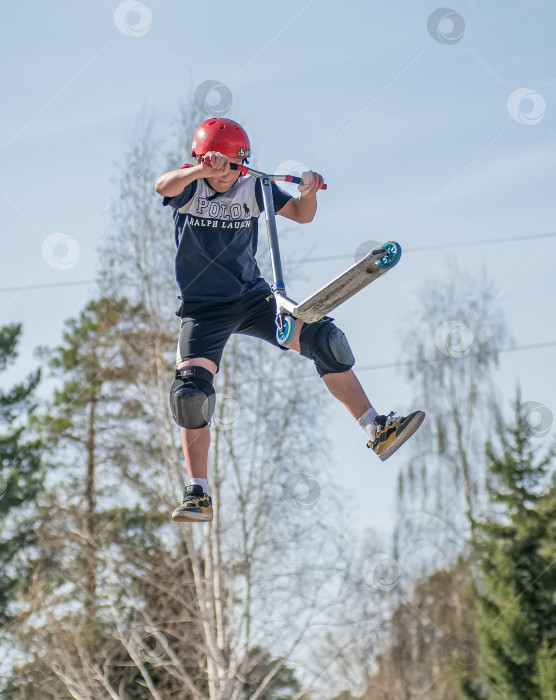 Скачать Россия, Красноярск 02 мая 2025г. Подросток на трюковом самокате в скейт-парке выполняет трюк во время прыжка. фотосток Ozero