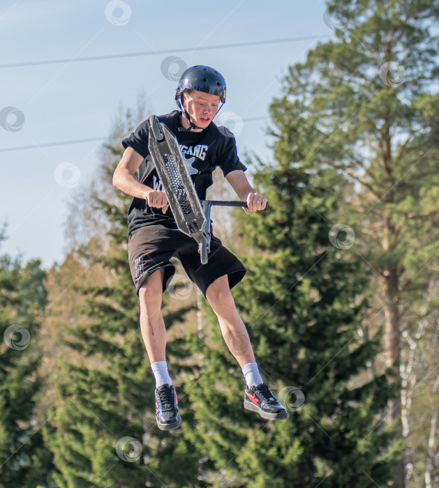 Скачать Россия, Красноярск 02 мая 2025г. Подросток на трюковом самокате в скейт-парке выполняет трюк во время прыжка. фотосток Ozero