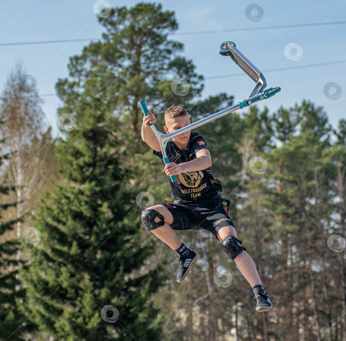 Скачать Россия, Красноярск 02 мая 2025г. Подросток на трюковом самокате в скейт-парке выполняет трюк во время прыжка. фотосток Ozero