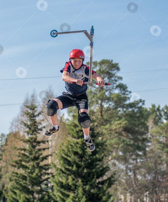 Скачать Россия, Красноярск 02 мая 2025г. Подросток на трюковом самокате в скейт-парке выполняет трюк во время прыжка. фотосток Ozero