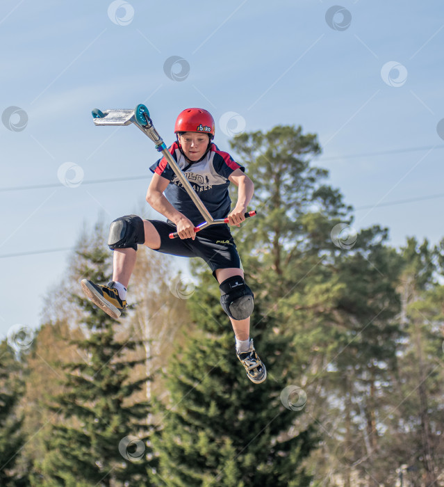 Скачать Россия, Красноярск 02 мая 2025г. Подросток на трюковом самокате в скейт-парке выполняет трюк во время прыжка. фотосток Ozero