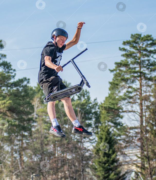 Скачать Россия, Красноярск 02 мая 2025г. Подросток на трюковом самокате в скейт-парке выполняет трюк во время прыжка. фотосток Ozero