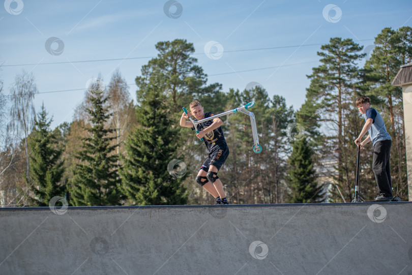 Скачать Россия, Красноярск 02 мая 2025г. Подросток на трюковом самокате в скейт-парке выполняет трюк во время прыжка. фотосток Ozero