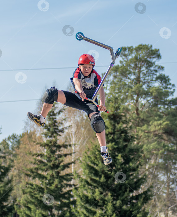 Скачать Россия, Красноярск 02 мая 2025г. Подросток на трюковом самокате в скейт-парке выполняет трюк во время прыжка. фотосток Ozero