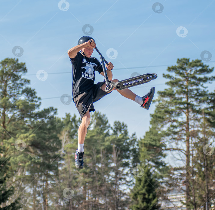 Скачать Россия, Красноярск 02 мая 2025г. Подросток на трюковом самокате в скейт-парке выполняет трюк во время прыжка. фотосток Ozero