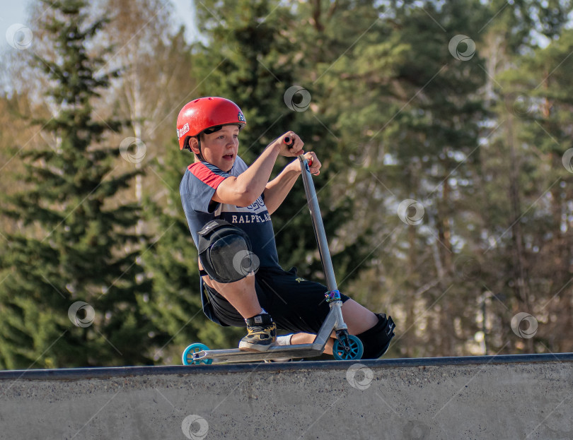 Скачать Россия, Красноярск 02 мая 2025г. Подросток на трюковом самокате в скейт-парке выполняет трюк во время прыжка. фотосток Ozero
