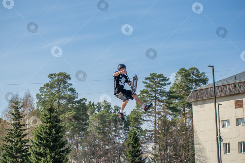 Скачать Россия, Красноярск 02 мая 2025г. Подросток на трюковом самокате в скейт-парке выполняет трюк во время прыжка. фотосток Ozero