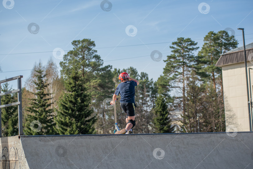 Скачать Россия, Красноярск 02 мая 2025г. Подросток на трюковом самокате в скейт-парке выполняет трюк во время прыжка. фотосток Ozero