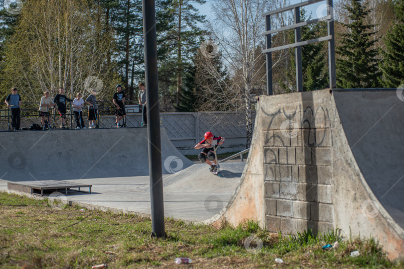 Скачать Россия, Красноярск 02 мая 2025г. Подросток на трюковом самокате в скейт-парке выполняет трюк во время прыжка. фотосток Ozero