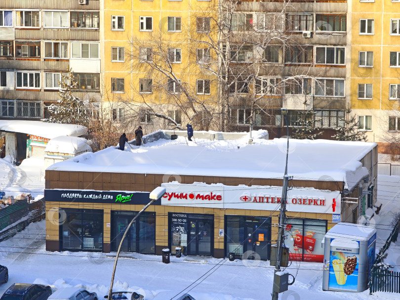 Скачать Чистка снега с крыши павильона. Уборка снега с крыши павильона. фотосток Ozero