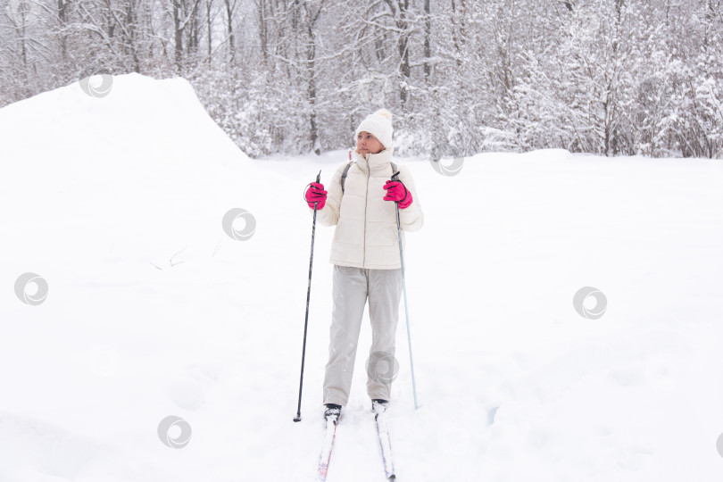 Скачать Лыжница в белом костюме в зимнем лесу. Концепция здорового образа жизни. Туристка в лесу на лыжах фотосток Ozero