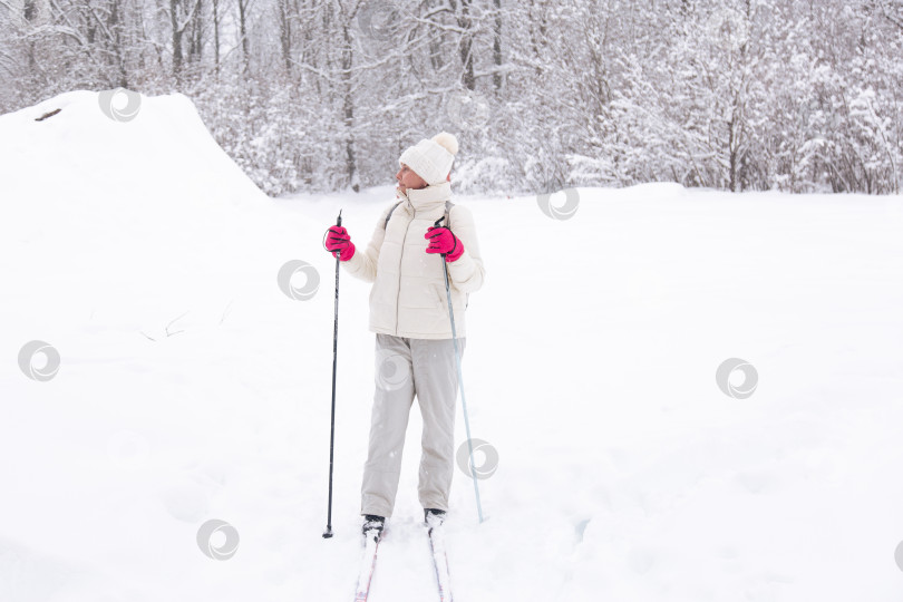 Скачать Лыжница в белом костюме в зимнем лесу. Концепция здорового образа жизни. Туристка в лесу на лыжах фотосток Ozero