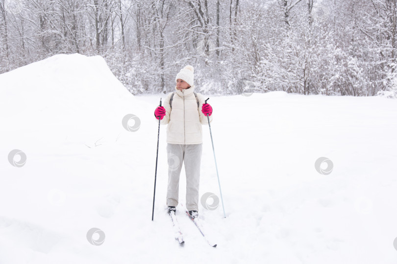 Скачать Лыжница в белом костюме в зимнем лесу. Концепция здорового образа жизни. Туристка в лесу на лыжах фотосток Ozero