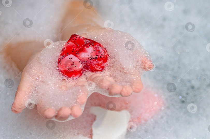 Скачать Детские ручки, держащие мыло в форме сердца с обильной пеной на светлом фоне фотосток Ozero