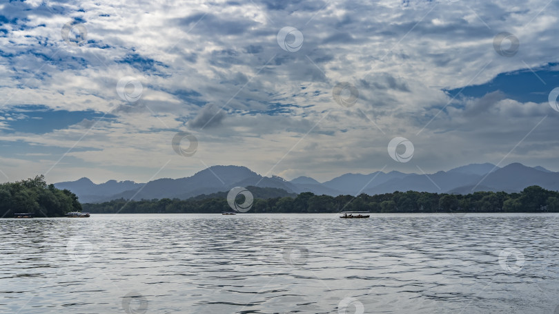 Скачать Красивое спокойное озеро. По воде плавают туристические лодки, катера-скороходы. фотосток Ozero