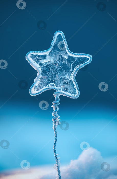 Скачать Ледяная звезда с замысловатыми морозными узорами на плетеной металлической проволоке, подсвеченная мягким голубым светом, олицетворяет холодную температуру и зимнюю красоту фотосток Ozero