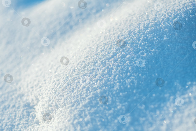 Скачать Свежевыпавший снег образует искрящийся текстурированный зимний фон, переливающийся в ярком солнечном свете мягкими тенями и нежными кристаллическими узорами, создавая спокойную сезонную картину фотосток Ozero