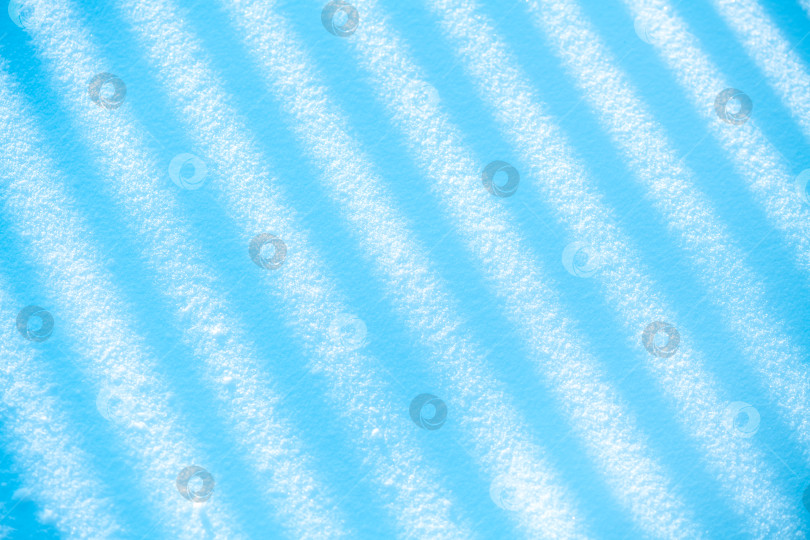 Скачать Зимняя снежная поверхность с интригующими абстрактными узорами из диагональных теневых полос создает прохладный сине-белый текстурный фон для сезонных или концептуальных дизайнов фотосток Ozero