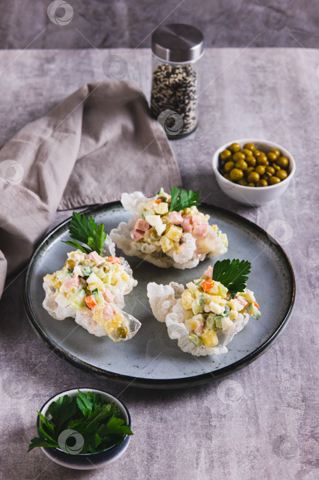 Скачать Салат Оливье в мисках из рисовой бумаги на тарелке на столе в вертикальном положении фотосток Ozero