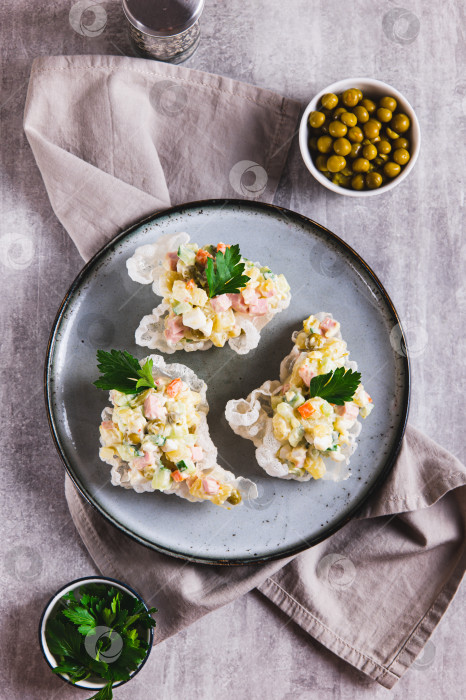 Скачать Салат Оливье в мисках из рисовой бумаги на тарелке, установленной на столешнице, в вертикальном положении фотосток Ozero