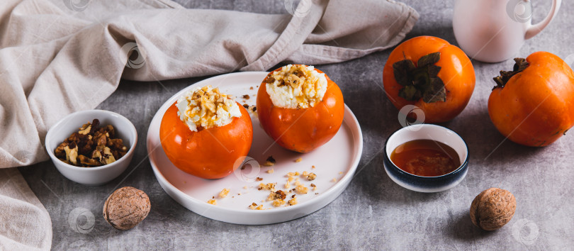Скачать Спелая хурма с начинкой из творога, меда и орехов на тарелке на веб-баннере "Стол" фотосток Ozero