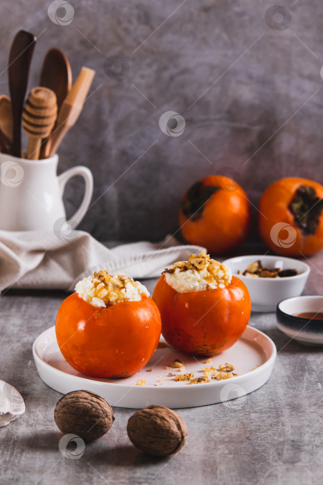 Скачать Спелая хурма с начинкой из творога, меда и орехов на тарелке на столе, вид сверху фотосток Ozero