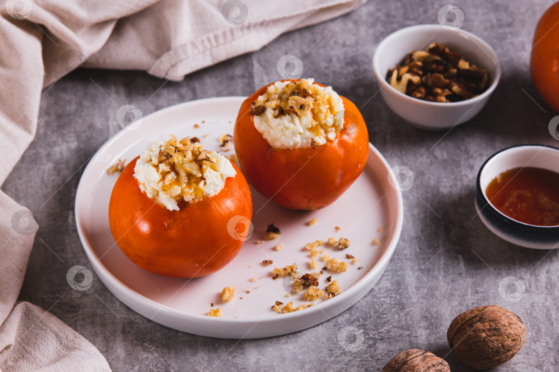 Скачать Сладкая хурма, фаршированная творогом и грецкими орехами, на тарелке на столе фотосток Ozero