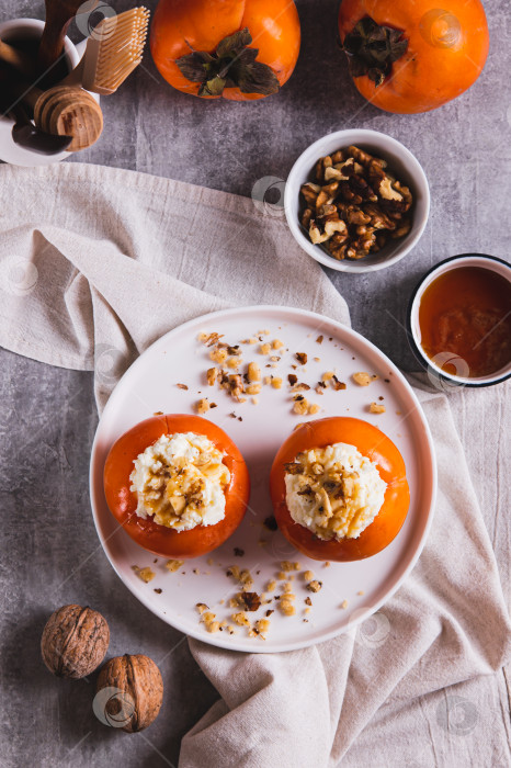 Скачать Сладкая хурма, фаршированная творогом и грецкими орехами, на тарелке в вертикальном положении фотосток Ozero