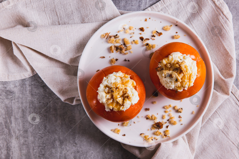 Скачать Крупный план спелой хурмы, начиненной творогом, медом и орехами, на тарелке, вид сверху фотосток Ozero