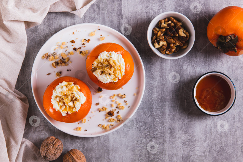 Скачать Спелая хурма с начинкой из творога, меда и орехов на тарелке на столе вид сверху фотосток Ozero