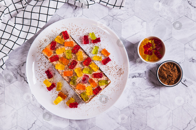 Скачать Шоколадный торт, украшенный мармеладными мишками, на тарелке на столе вид сверху фотосток Ozero