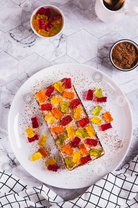 Скачать Сладкий тирамису с мармеладными мишками на тарелке на столешнице в вертикальном положении фотосток Ozero