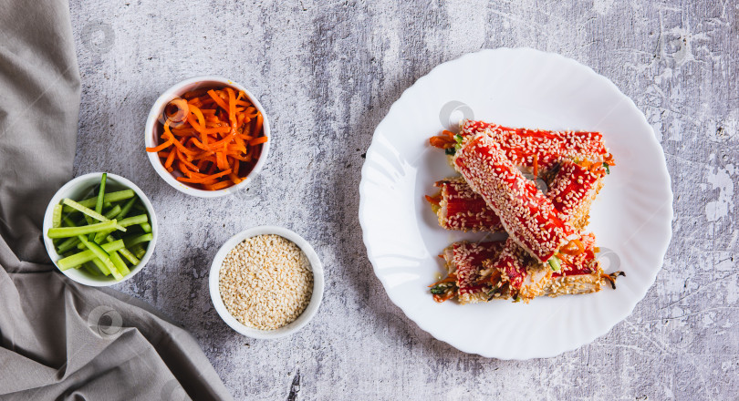 Скачать Роллы из запеченных крабов с огурцом и морковью в кунжуте на тарелке вид сверху веб-баннер фотосток Ozero