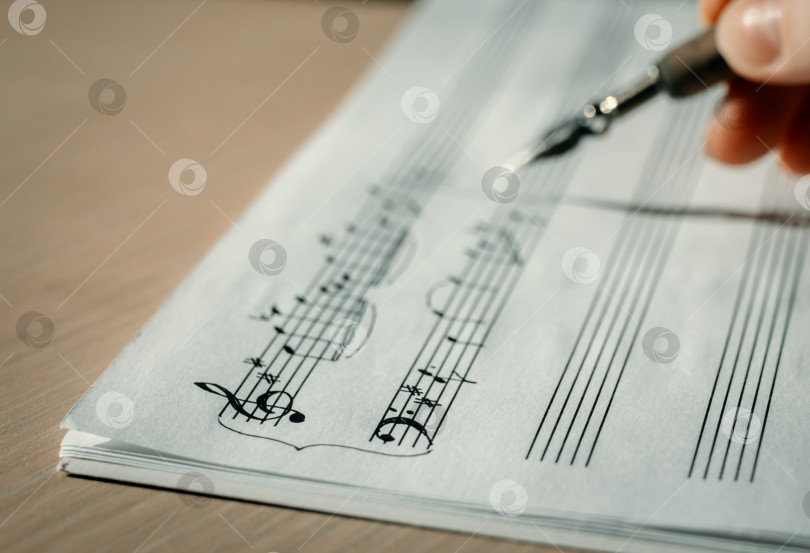 Скачать Скрипичный ключ и ноты крупным планом, лист с заметками на фоне руки с чернильной ручкой фотосток Ozero