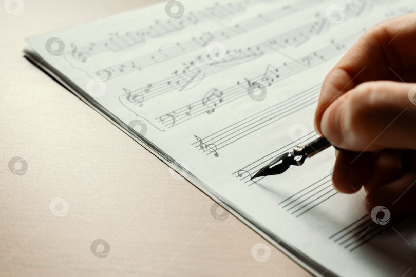 Скачать Рука рисует басовый ключ в нотной тетради, фон для рукописных заметок фотосток Ozero