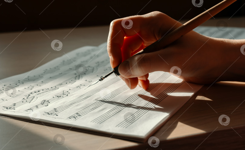 Скачать Рука с чернильной ручкой, делающая заметки в записной книжке, освещенной боковым светом фотосток Ozero