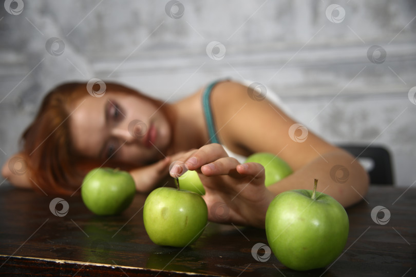 Скачать Молодая женщина сидит  за столом с яблоками фотосток Ozero