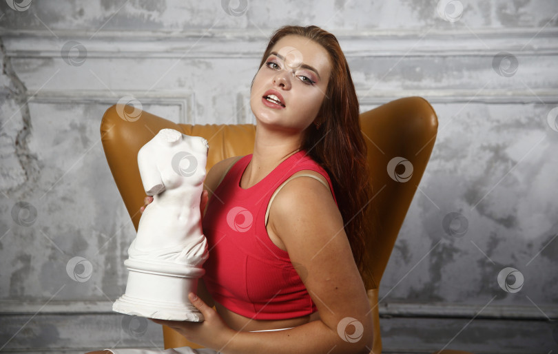 Скачать Красивая девушка в красной кофте позирует в студии фотосток Ozero