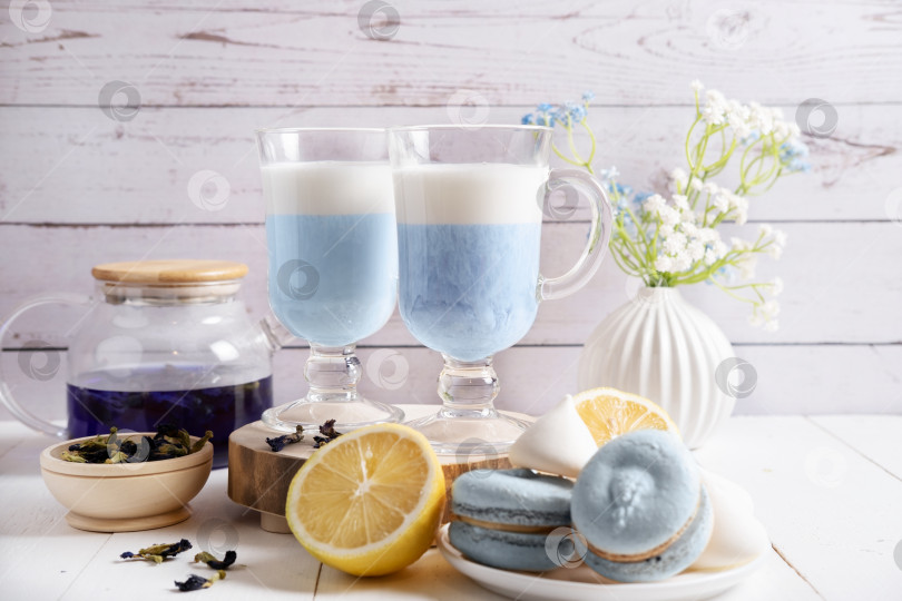 Скачать Тайский голубой чай Анчан со взбитыми сливками в прозрачном стакане. Композиция со сладостями и лимоном фотосток Ozero