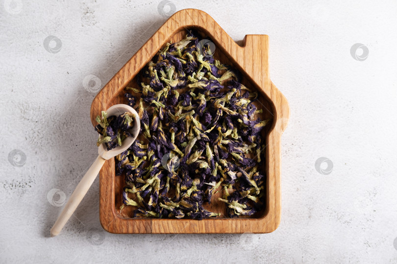 Скачать Высушенные цветы голубого тайского чая анчан в деревянной тарелке в виде домика. Полезный напиток для диеты, детоксикации фотосток Ozero