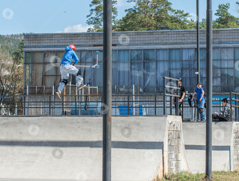 Скачать Россия, Красноярск 02 мая 2025г. Подросток на трюковом самокате в скейт-парке выполняет трюк во время прыжка. фотосток Ozero