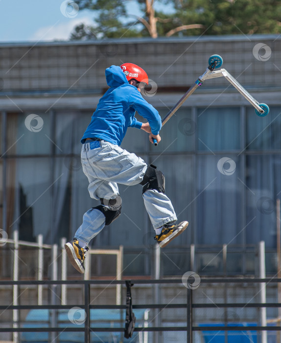 Скачать Россия, Красноярск 02 мая 2025г. Подросток на трюковом самокате в скейт-парке выполняет трюк во время прыжка. фотосток Ozero