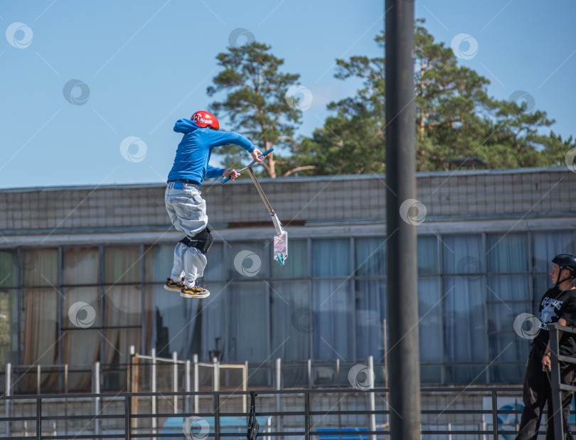 Скачать Россия, Красноярск 02 мая 2025г. Подросток на трюковом самокате в скейт-парке выполняет трюк во время прыжка. фотосток Ozero