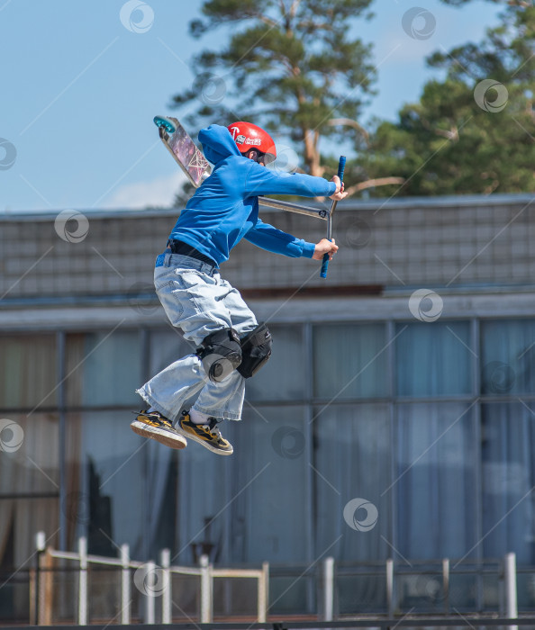Скачать Россия, Красноярск 02 мая 2025г. Подросток на трюковом самокате в скейт-парке выполняет трюк во время прыжка. фотосток Ozero