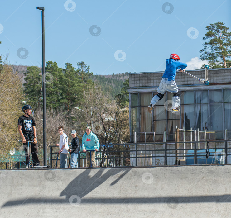 Скачать Россия, Красноярск 02 мая 2025г. Подросток на трюковом самокате в скейт-парке выполняет трюк во время прыжка. фотосток Ozero